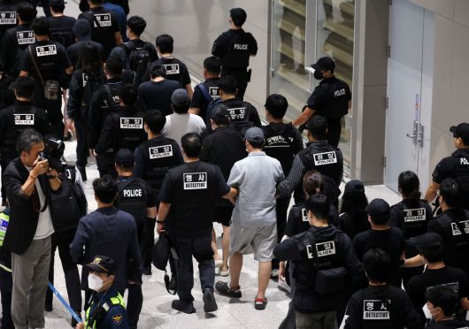 캄보디아에서 보이스피싱(전화금융사기) 등 범죄에 가담했다가 현지 경찰 조사를 받고 이민 당국에 구금됐던 한국인 64명이 18일 오전 인천국제공항 제2터미널을 통해 송환되고 있다. 공동취재사진