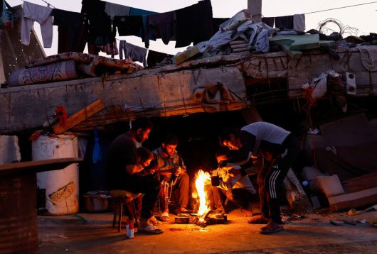 19일(현지시각) 가자지구 북부 지역에서 팔레스타인 주민들이 나무 장작으로 피운 모닥불 곁에 모여 추위를 피하고 있다. 가자지구에선 최근 내린 겨울 폭우에 팔레스타인 피난민들이 추위로 고통받고 있지만, 이스라엘은 가자지구 내로 연료 반입을 제한하고 있다. 로이터 연합뉴스