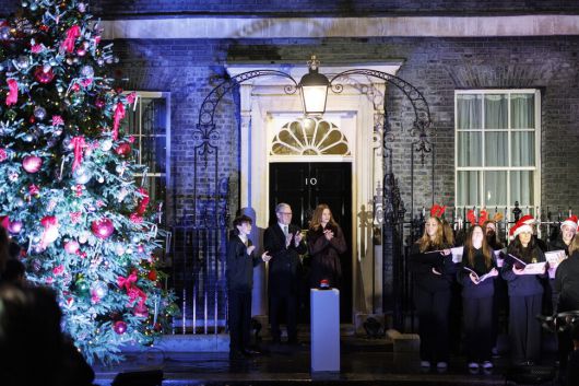 1일(현지시각) 키어 스타머 영국 총리 부부가 런던 다우닝가 10번지 총리실 앞에서 크리스마스 트리 조명을 켠 후 캐럴을 듣고 있다. 런던/EPA 연합뉴스