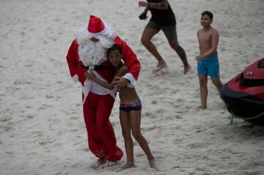 4일(현지시각) 한 브라질 소년이 크리스마스 선물을 나눠주기 위해 제트 스키를 타고 리우데자네이루의 코파카바나 해변에서 열린 어린이 행사에 도착한 산타클로스 복장을 한 소방관을 껴안고 있다.리우데자네이루/AP 연합뉴스