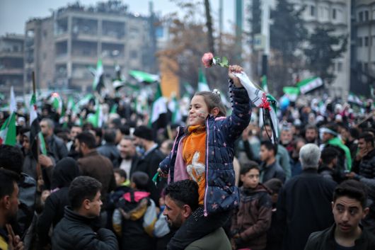 8일(현지시각) 시리아 이들립에서 해방기념일을 맞아 열린 기념 행사에서 한 소녀가 아빠의 어깨 위에 앉아 기뻐하고 있다. EPA 연합뉴스