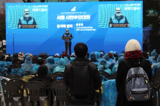 20일 오후 서울 종로구 보신각 광장에서 열린 1229 무안공항 제주항공 여객기 참사 1주기 서울시민추모대회에서 유가족 김영헌씨가 유가족 편지를 낭독하는 동안 시민들이 이를 지켜보고 있다. 김태형 기자