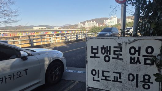 울산 남구 삼호교 들머리에 보행로가 없으니 인도교(옛 삼호교)를 이용하라는 안내판이 붙어 있다. 다리 너머로 상판이 무너진 무지개색 난간의 옛 삼호교가 보인다. 주성미 기자