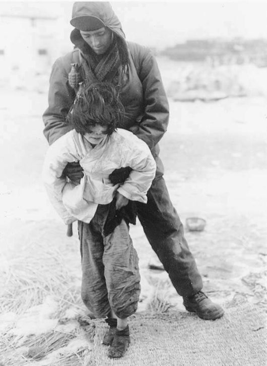 6·25전쟁 당시 앞이 보이지 않는 소녀가 부상을 당한 채 미군의 부축을 받고 있다. 미국 국립문서관리청(NARA) 소장. ‘유령 연구’의 원서 표지에 쓰인 사진이다. 동녘 제공