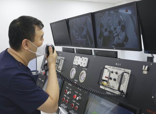 김련 전담간호사가 고압산소챔버에서 치료를 받는 환자들과 이야기를 하고 있다.