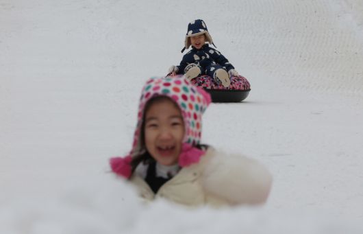 겨울 테마파크 2026 노원 눈썰매장 장애인 가족 초청 행사가 열린 12일 오전 서울 노원구 서울과학기술대학교 종합운동장에서 김세린(앞·6), 김세준(4) 어린이가 눈썰매를 타고 있다. 김영원 기자 forever@hani.co.kr