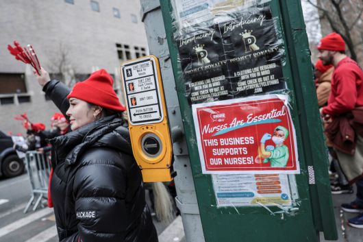 뉴욕주간호사협회 소속 조합원들이 지난 14일(현지시각) 맨해튼 마운트 시나이 병원 들머리에서 집회를 가운데 거리에 조합원들이 붙인 파업 안내문이 붙어 있다. 뉴욕/로이터 연합뉴스