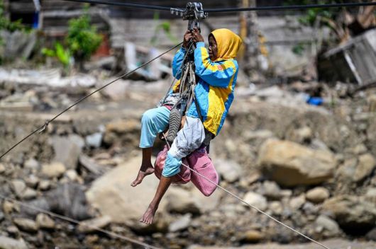 급류성 홍수로 인근 마을이 파괴된 가운데 지난 6일 인도네시아 아체 고원 지역 케톨에서 한 여성이 끊긴 길을 대신해 밧줄에 의지해 강을 건너고 있다. AFP 연합뉴스