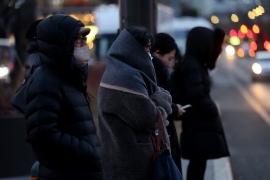 절기 대한(大寒)을 하루 앞두고 한파주의보가 예고된 19일 저녁 서울 종로 광화문 네거리에서 두꺼운 외투를 입은 시민들이 횡단보도에서 신호를 기다리고 있다. 연합뉴스