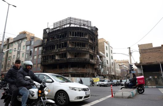 19일(현지시각) 이란 테헤란에서 반정부 시위 기간 불탄 이란 멜리은행의 지점 주위로 시민들이 차를 타고 이동하고 있다. EPA 연합뉴스