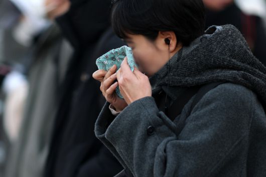 한파특보가 발령된 20일 서울 세종대로 사거리에서 한 시민이 손수건으로 얼굴을 닦고 있다. 연합뉴스