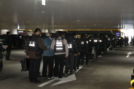 캄보디아에서 우리 국민 869명에게 약 486억원을 편취한 한국인 피의자 73명이 전세기로 23일 오전 인천국제공항 제2여객터미널 도착해 호송차를 타기 위해 줄을 서 있다. 정용일 선임기자 yongil@hani.co.kr