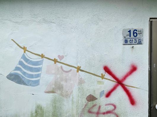 문현동 안동네 벽화마을에 그려진 빨랫줄 벽화. 퇴거 완료를 뜻하는 'X'자 표식이 겹쳐있다. 김시덕 제공