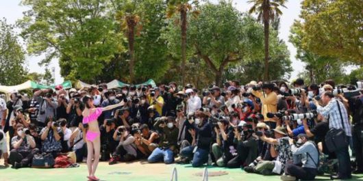 지난해 여름 일본 사이타마현립 수상공원에서 열린 수영복 촬영회 현장 사진. 중학생 모델이 수영복을 입은 모습을 100여 명의 남성이 촬영하고 있다. 트위터 캡처