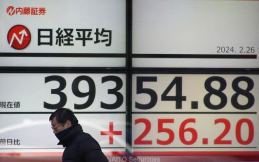 한 일본 시민이 지난달 26일 도쿄 시내에서 일본 닛케이225 평균주가(닛케이지수)가 적혀 있는 증시 현황판 앞을 지나가고 있다. 도쿄=AFP 연합뉴스