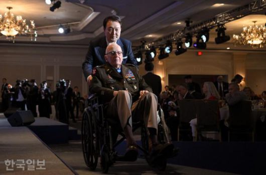 윤석열 대통령이 지난해 4월 25일 미국 워싱턴의 한 호텔에서 열린 한미동맹 70주년 기념 오찬에 참석해 생전 랠프 퍼켓 주니어 미 육군 예비역 대령의 휠체어를 밀고 있다. 이날 윤 대통령은 고 퍼켓 주니어 대령에게 태극무공훈장을 수여했다. 워싱턴=서재훈 기자