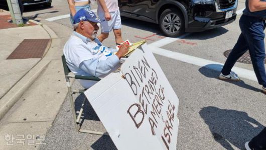 미국 민주당 지지자 밥 쿤스트가 14일 공화당 전당대회 장소인 위스콘신주 밀워키 파이서브포럼 입구 검색대 앞에서 ‘바이든(미국 대통령)이 미국과 이스라엘을 배신했다’고 쓰인 팻말을 세워 둔 채 간이의자에 앉아 있다. 밀워키=권경성 특파원