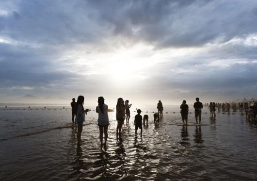 지난 26일 다대포해수욕장을 찾은 여행객들이 짙은 구름 속에서 잠시 햇살이 비치자 인증사진을 찍고 있다. 근래 노을 명소로 각광받는 해변이다.