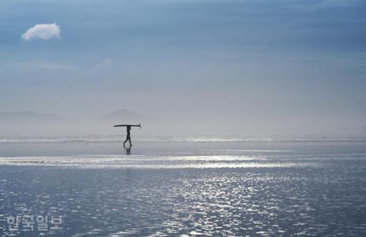 한 서퍼가 바닷물이 찰랑거리는 다대포해수욕장을 가로지르고 있다. 수시로 해무가 올라 몽환적인 분위기를 자아낸다.