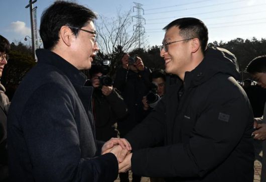 김경수(왼쪽) 전 경남도지사와 국민의힘 김상욱 의원이 24일 오전 광주 북구 운정동 국립5·18민주묘지 민주의문 앞에서 악수하고 있다. 뉴시스