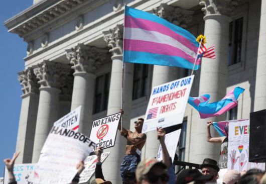 도널드 트럼프 미국 행정부에 반대하는 '핸즈 오프(Hands off·손 떼)' 시위가 전국적으로 벌어지고 있는 가운데, 5일 유타주 솔트레이크시티에서 한 시위자가 트랜스젠더를 상징하는 깃발을 치켜들고 있다. 솔트레이크시티=로이터 연합뉴스