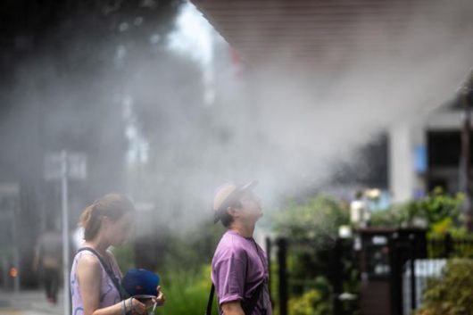 외국인 관광객들이 지난해 8월 일본 도쿄 긴자 시내에서 더위를 식히기 위해 스프링클러 앞에 서 있다. 도쿄=AFP 연합뉴스