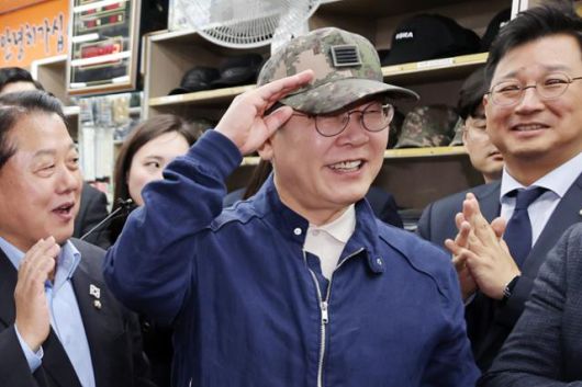 민심을 청취하는 '경청 투어'에 나선 이재명 더불어민주당 대선 후보가 2일 강원도 화천군 화천공영버스터미널 인근의 한 군장점에서 김병주 최고위원이 사준 병장 계급장이 달린 육군 모자를 써보고 있다. 뉴시스
