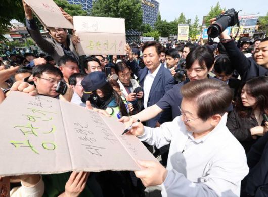 민심을 청취하는 '경청 투어'에 나선 이재명 더불어민주당 대선 후보가 7일 전북 전주시 완산구 풍남문 인근에서 공판 연기를 환영하는 지지자의 응원 피켓에 사인을 해주고 있다. '공판 연기 환영, 대통령은 국민이 뽑습니다'라고 적힌 피켓에 이 후보는 '맞습니다'라고 쓰고 있다. 전주=뉴시스