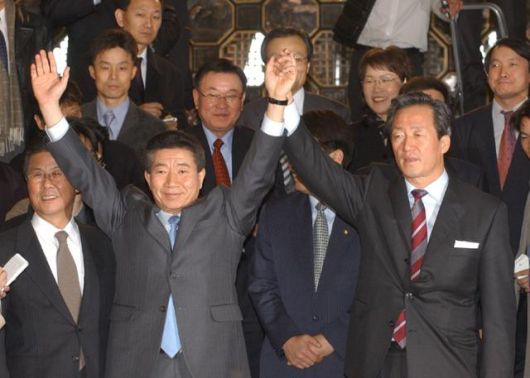 2002년 11월 25일 노무현(앞줄 왼쪽) 새천년민주당 대선 후보와 정몽준(오른쪽) 국민회의21 대선 후보가 단일화 합의 직후 국회의사당 귀빈 식당에서 회동을 마친 뒤 함께 손을 들고 있다. 연합뉴스
