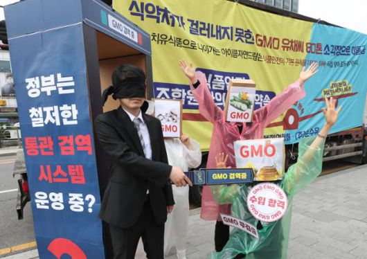 소비자기후행동 회원들이 12일 오전 서울 종로구 한 호텔 앞에서 'GMO 수입·통관 제도 개혁 및 GMO 완전표시제 도입 촉구 기자회견을 열고 유기농 유채씨 GMO 혼입 건 및 미승인 LMO 주키니 호박 유통 건 등 허술한 GMO 수입·통관 제도와 GMO 관리 부실에 대한 항의 퍼포먼스를 하고 있다. 뉴시스
