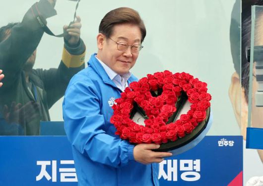 이재명 더불어민주당 대선 후보가 20일 경기 고양시 일산문화공원에서 유세에 앞서 선거도장 마크 모양의 꽃다발을 선물받고 있다. 고영권 기자