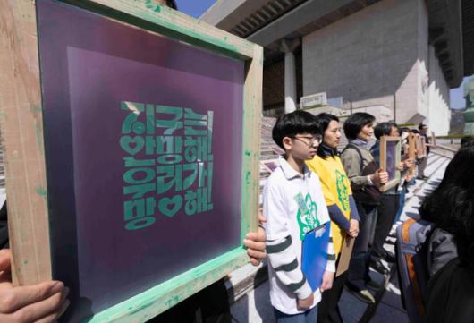 기후위기비상행동과 기후정치바람 회원들이 지난달 15일 서울 종로구 세종문화회관 앞에서 열린 기후 단일 의제 대선 TV 토론회 촉구 기자회견에서 캠페인 슬로건이 적힌 실크스크린을 들고 서 있다. 뉴시스