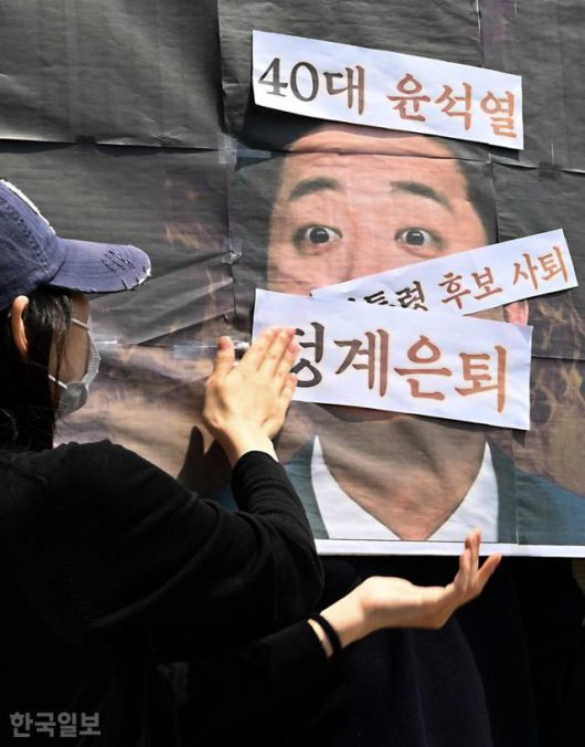29일 서울 영등포구 개혁신당 당사 앞에서 열린 이준석 대통령 선거 후보 사퇴 촉구 기자회견에서 주최 측인 한국대학생진보연합이 이 후보 사진에 비판 문구를 붙이는 퍼포먼스를 하고 있다. 강예진 기자