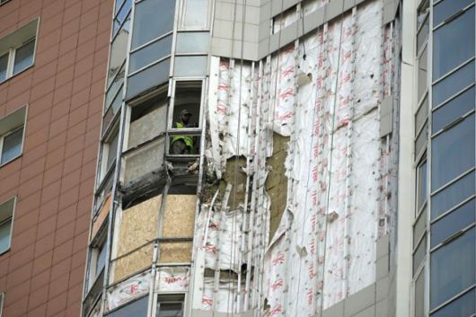 지난달 29일(현지 시간) 러시아 모스크바 베르나드스키 대로에 있는 미락스파크 주거단지 아파트 창문 사이로 근로자가 작업하고 있다. 이 아파트 단지는 우크라이나의 드론 공격으로 피해를 입은 것으로 전해졌다. 모스크바=AP 뉴시스