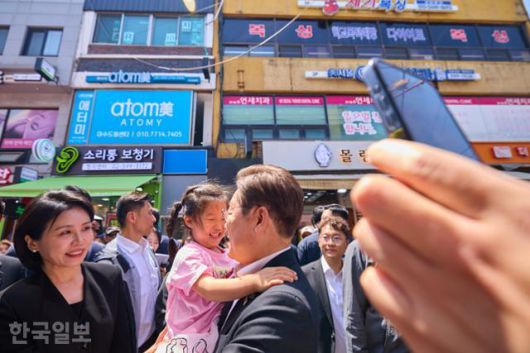 이재명 대통령과 김혜경 여사가 6일 서울 동작구 남성시장을 방문해 한 아이를 안아주고 있다. 대통령실 제공