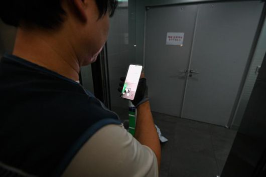 쿠팡 퀵플렉서 배송기사 송정민(가명)씨가 4일 오피스 건물에서 물품을 배송한 뒤 화물용 엘리베이터 문 사이로 '배송 완료' 인증 사진을 찍고 있다. 그는 인증 사진을 찍다가 엘리베이터 문이 닫히려고 하면 급하게 '열림' 버튼을 누르고, 이내 또 일이 마무리되면 다시 '닫힘' 버튼을 누르기를 반복했다. 남동균 인턴기자