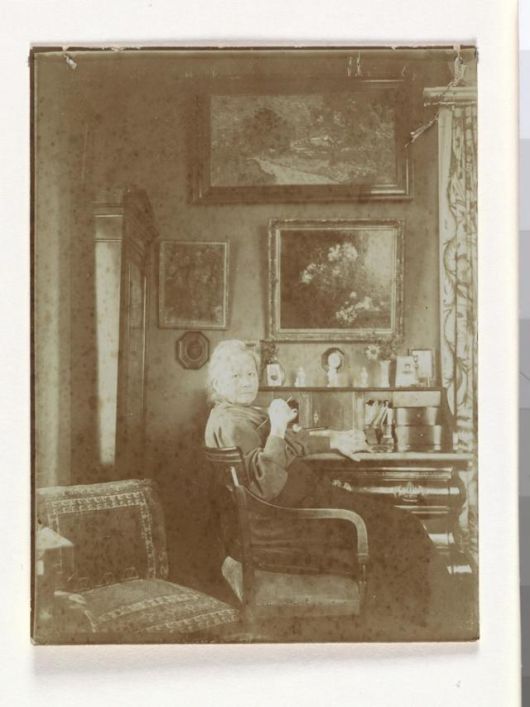 네덜란드 암스테르담의 자택 거실 책상 앞에 앉아 있는 요 반 고흐 봉어르의 모습. 1909년으로 추정된다. 책상 뒤편 벽에 빈센트 반 고흐의 그림 '은선초 꽃병'과 '황혼 풍경'이 보인다. 아트북스 제공