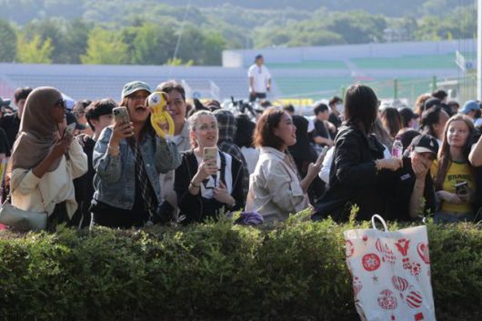 그룹 방탄소년단의 팬덤 아미가 11일 경기 연천군 연천공설운동장에서 이날 전역하는 두 멤버 지민·정국을 기다리며 환하게 웃고 있다. 연합뉴스