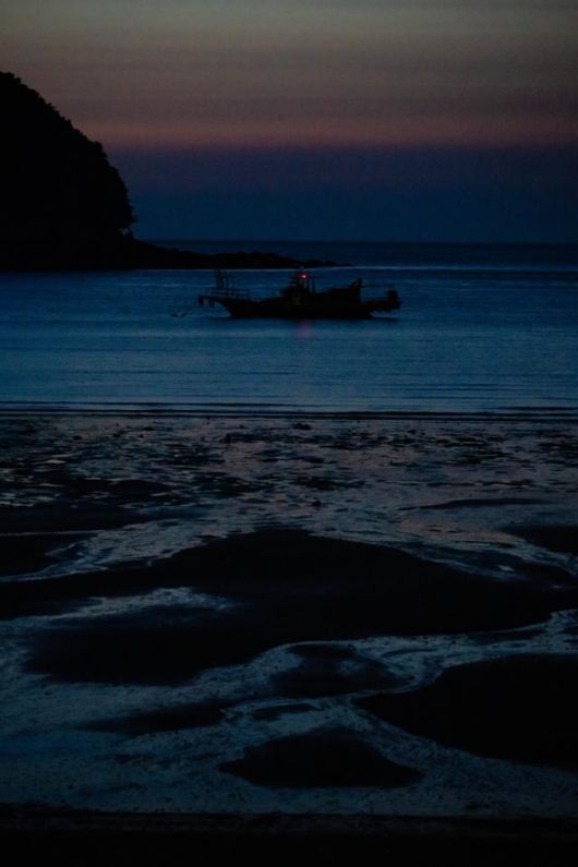 밤이 내린 대이작도의 갯벌 뒤로 작은 어선이 떠 있다.