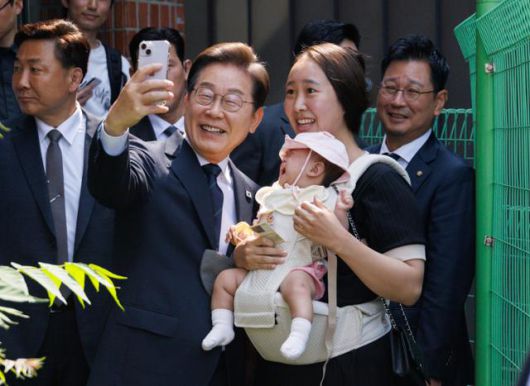 당시 이재명 더불어민주당 대통령 후보가 제21대 대통령선거 사전투표 첫날인 지난달 29일 서울 서대문구 구 신촌동주민센터에서 청년들과 사전투표를 마친 뒤 아이를 안은 주민과 셀카를 찍고 있다. 뉴스1