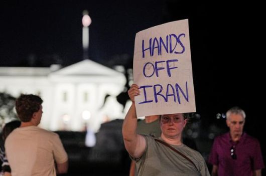 이란 핵 시설에 대한 미국의 공습이 벌어진 21일 워싱턴 D.C. 라파예트 공원에서 미국의 개입에 반대하는 시위자가 포스터를 들고 있다. 워싱턴=로이터 연합뉴스