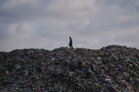 한 팔레스타인 어린이가 24일 가자지구 중부 알 자와이다에서 쓰레기 더미 위를 걷고 있다. 가자지구=AP 연합뉴스