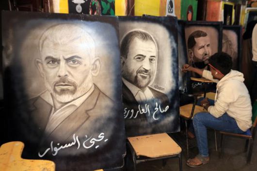 예멘의 한 예술가가 23일 수도 사나에서 열린 '이란과 연대를 위한 공동 예술 워크숍'에서 지난해 사망한 하마스 수장 야히아 신와르(왼쪽부터)와 하마스 부총재 살레 알 아로리를 그린 그림 옆에서 작업을 하고 있다. 사나=EPA 연합뉴스