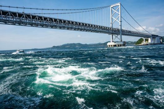 나루토해협의 소용돌이 뒤로 관조선과 나루토대교가 보인다.
