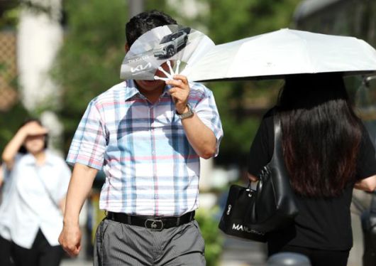 폭염이 계속되는 10일 서울 종로구 거리에서 시민들이 부채와 양산으로 햇볕을 피하며 걸어가고 있다. 뉴시스