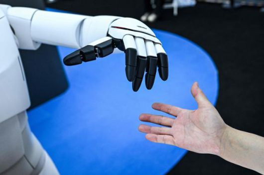 지난 7월 상하이에서 열린 세계 AI 콘퍼런스에서 한 사람이 휴머노이드 로봇과 손을 잡으려고 하고 있다. 상하이=AFP 연합뉴스