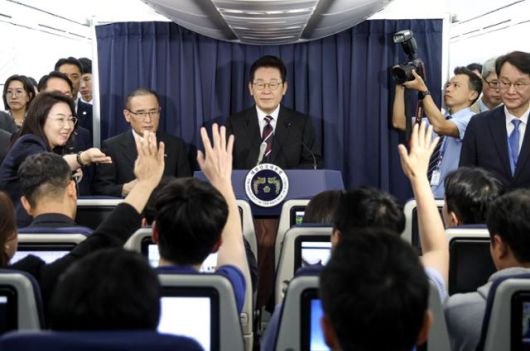 이재명 대통령이 24일(현지시간) 일본 도쿄 하네다공항 이륙 뒤 한미 정상회담을 위해 미국 워싱턴 향하는 공군 1호기 기내에서 기자간담회를 하며 취재진의 질문을 받고 있다. 연합뉴스