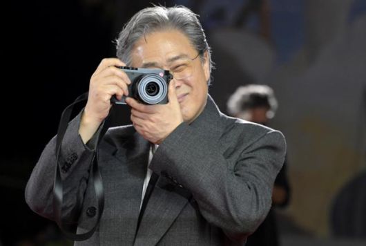 박찬욱 감독이 29일 이탈리아 베니스 리도섬의 살라 그란데에서 열린 제82회 베니스국제영화제 '어쩔수가없다' 공식 상영회를 앞두고 레드 카펫에서 카메라를 들고 사진을 찍는 포즈를 하고 있다. 베니스=EPA 연합뉴스