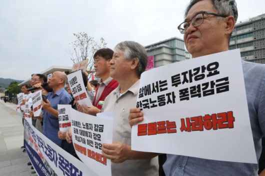 9일 서울 종로구 주한 미국대사관 인근에서 열린 ‘굴욕적 대미 투자 강요 및 한국 노동자 폭력적 인권 유린 미국 트럼프 정부 규탄’ 시민사회단체 기자회견의 참석자들이 손 팻말을 들고 서 있다. 뉴스1