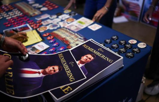 미국 애리조나주 템피의 애리조나 주립대학교 캠퍼스 데저트 파이낸셜 아레나에서 15일 우익 활동가 찰리 커크를 추모하는 집회가 열린 가운데 참석자들이 전단지와 버튼을 들고 있다. 템피=AFP 연합뉴스